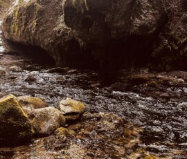 Prírodná Brestovská vyvieračka v Orave, zdroj živé vody v krásnej prírode. Voda z Brestovskej vyvieračky v Orave, obklopená skalami a prírodou.