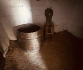 Staré drevené nádoby a nástroj v historickej miestnosti, autentická atmosféra.