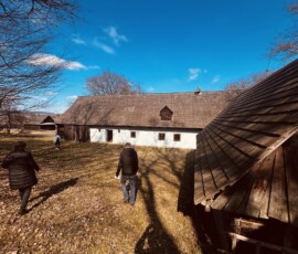Skupina ľudí prechádza starobylou dedinskou krajinou na Slovensku.