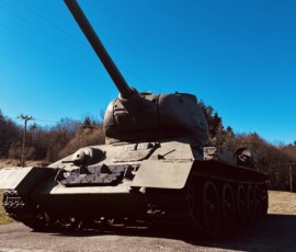 Tank na ceste v prírodnom prostredí počas slnečného dňa.