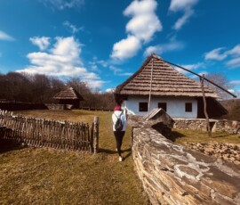Tradičný slovenský dom Šuhajovci na ceste s modrou oblohou a oblakmi.