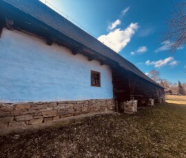 Drevenica na cestách s bielou fasádou a kamenným základom, ideálna pre turistov a milovníkov tradičn.