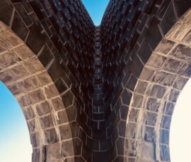Impozantná kamenná veža s modernou architektúrou na oblohe, pohľad zdola.