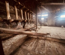 Interiér historickej budovy v Šuhajovcoch s drevenými prvkami a starým podlahovým povrchom.