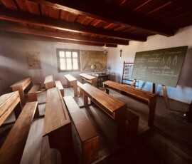 Interiér tradičnej slovenskej školy s lavicami a tabuľou.