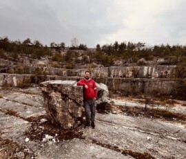 Turista stojaci pri veľkom kameni v prírodnom prostredí, objavovanie krásy Slovenska, outdoorové akt.