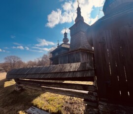Drevený kostol na vidieku s modrou oblohou a oblakmi, zachytený počas dňa.